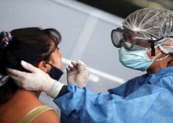 A healthcare worker takes a swab sample from a woman to be tested for the coronavirus disease (COVID-19), at a bus terminal  in Buenos Aires, Argentina January 12, 2021. REUTERS/Agustin Marcarian - RC2H6L9JU10A